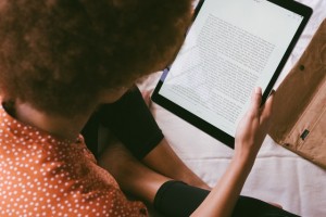 Photo d'une femme de dos lisant sur une tablette