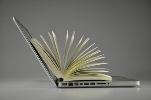 Photo d'un ordinateur portable ouvert avec un livre ouvert sur son écran et clavier